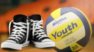 a pair of black sneakers next to a volleyball